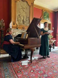 De voorstelling Jane Austens salon door sopraan Charlotte Houberg en pianiste Heleen Vegter op Landgoed Singraven, Denekamp. Heleen Vegter achter de piano, Charlotte Houberg aan het zingen.